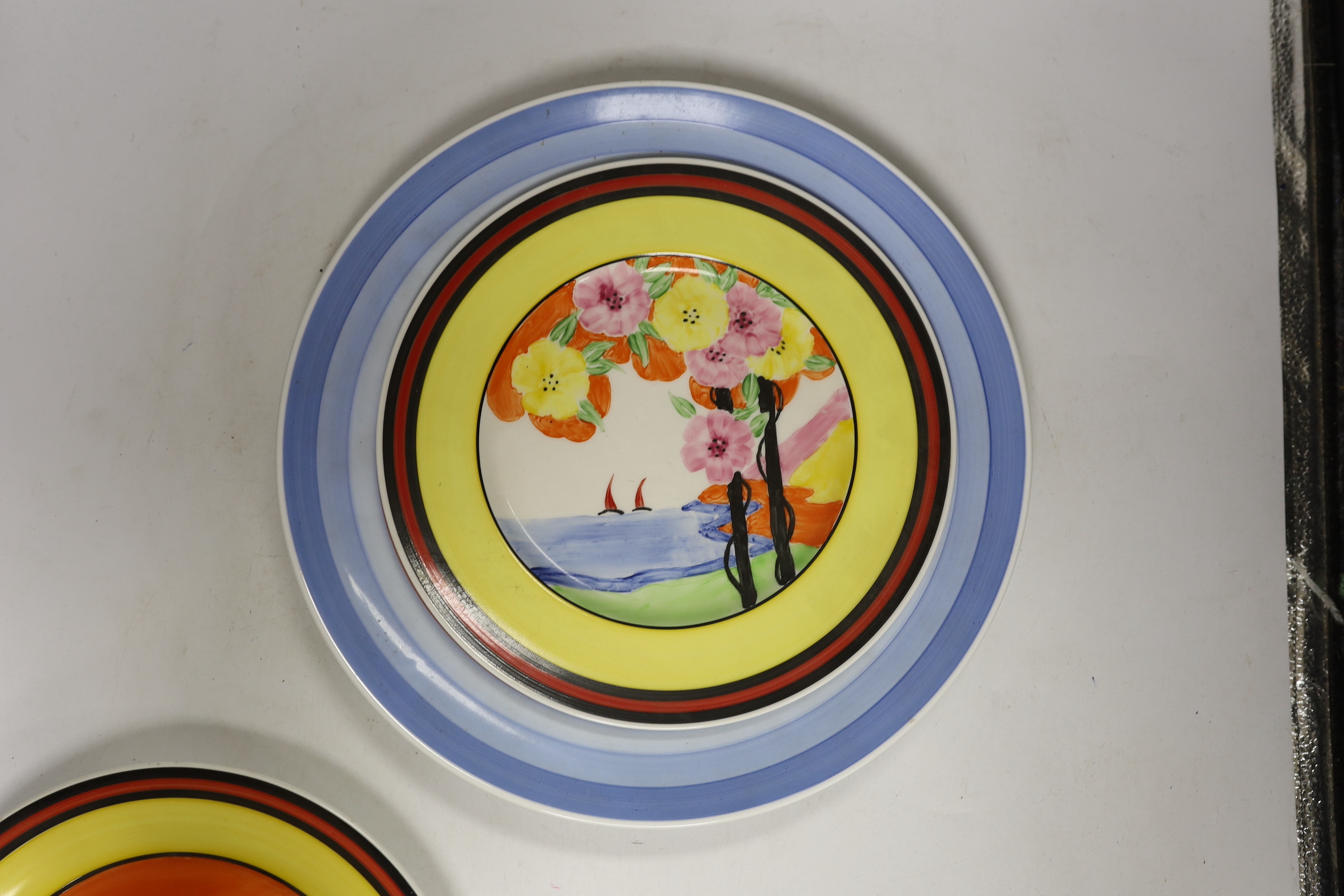 Four Clarice Cliff style plates, a similar vase and a jar and cover, tallest 31cm